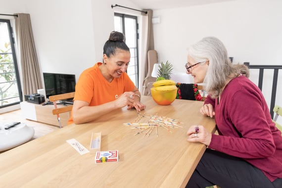 Une auxiliaire de vie aide un senior à améliorer sa mémoire grâce aux jeux de société