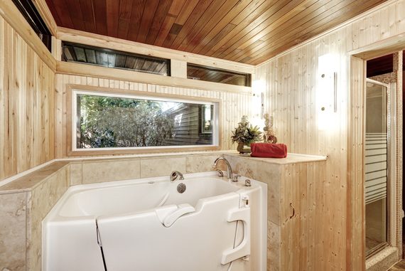 Photo d'une baignoire avec porte installée dans une salle de bain en bois